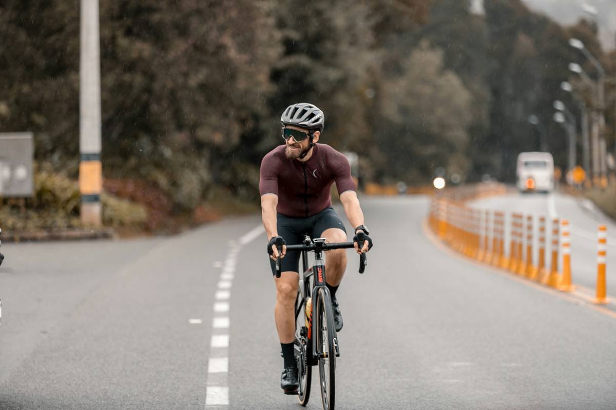 A cyclist sprinting on a road bike in bright sunlight.