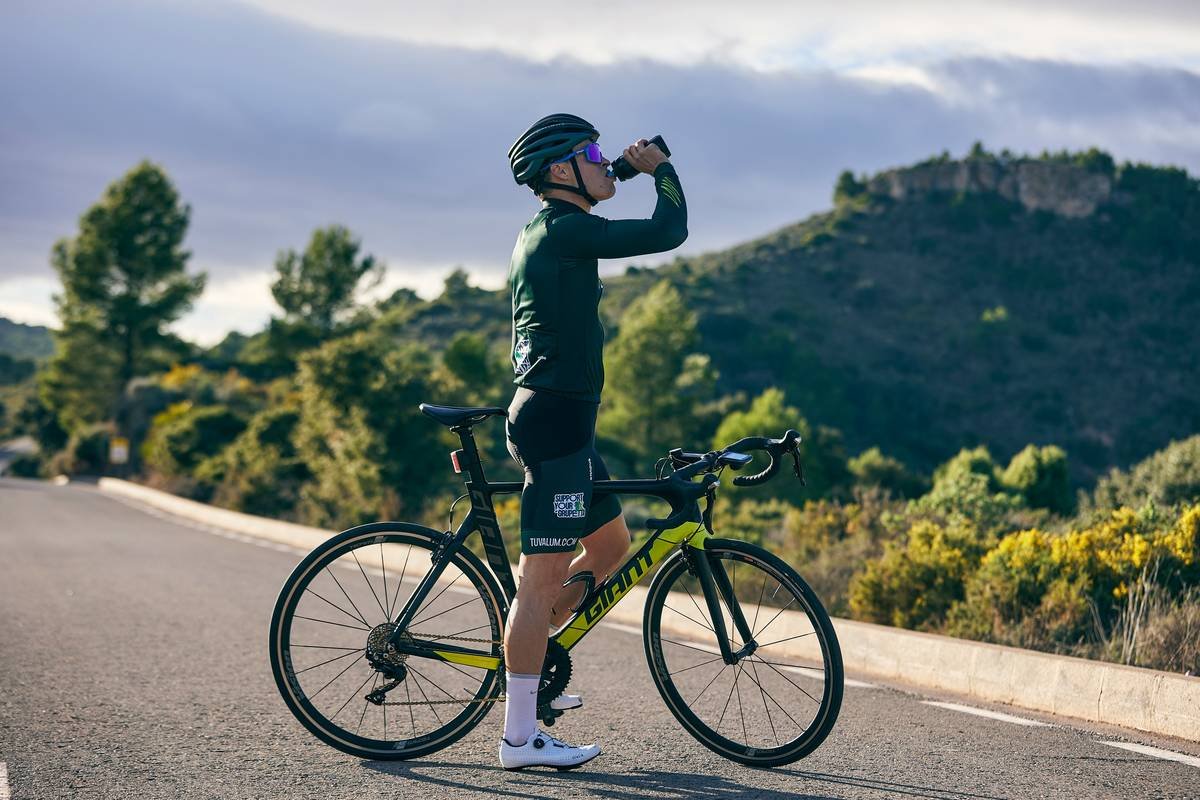a man standing next to a bike drinking water