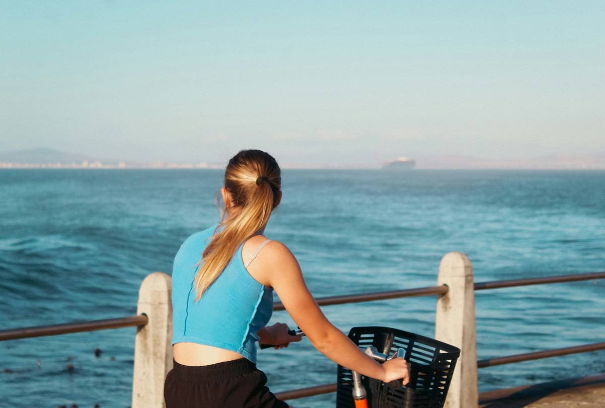 Woman riding a bike by the sea.