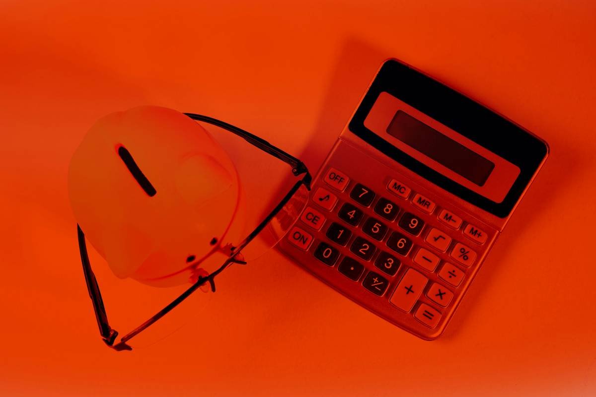 Calculator, helmet and glasses on a red background. Business concept.
